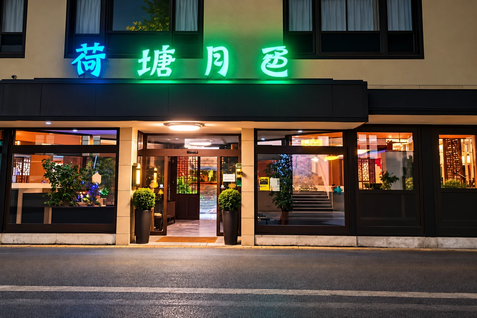 Der Eingang des Goldener Lotus am Abend: chinesische Leuchtschrift in Blau und Grün über dem dunklen Vordach, eine Glastür mit Holzgitter, links und rechts je eine runde Kübelpflanze, beleuchtete Fenster.